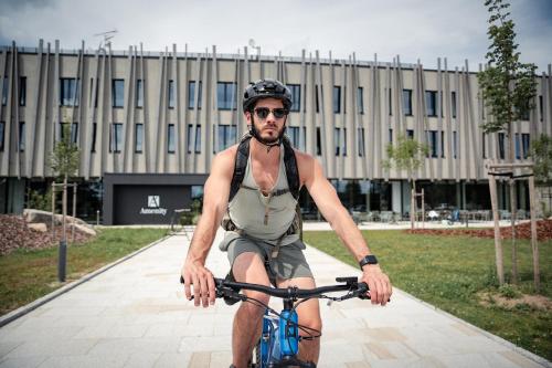 a man riding a bike in front of a building at Amenity Hotel & Resort Česká Kanada in Nová Bystřice