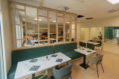 a dining room with two tables and chairs at Nemea Appart Hotel La Boetie Bordeaux Pessac in Pessac
