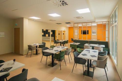 a restaurant with tables and chairs in a room at Nemea Appart Hotel La Boetie Bordeaux Pessac in Pessac