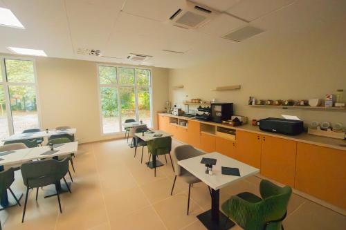 a dining room with tables and chairs and a kitchen at Nemea Appart Hotel La Boetie Bordeaux Pessac in Pessac