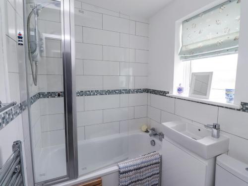 a bathroom with a tub and a sink and a shower at 51 Longstone Park in Chathill