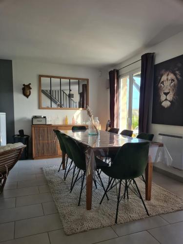 a dining room with a table and green chairs at Maison Gallardon in Gallardon