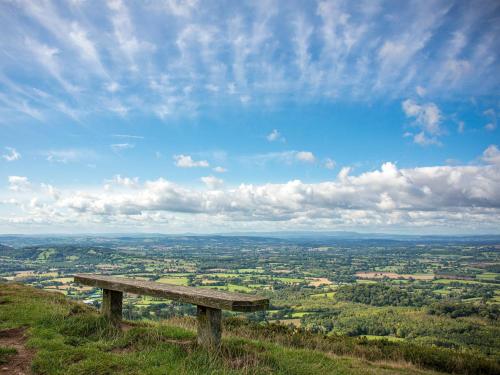 a wooden bench sitting on top of a hill at Yarlington Mill in Ledbury