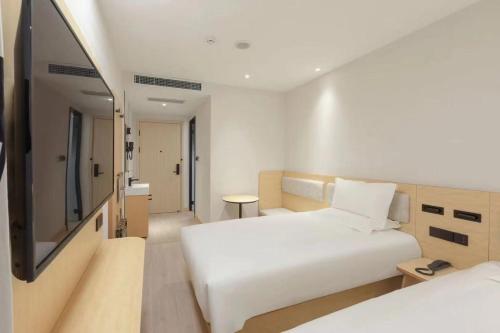 a hotel room with two beds and a flat screen tv at Hi Inn Beijing Daxing Zaoyuan Subway Station in Beijing
