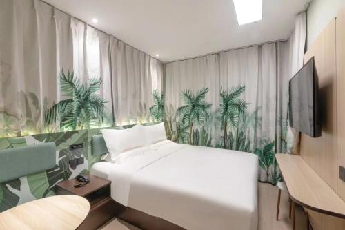 a bedroom with a white bed and a mural of palm trees at Hi Inn Beijing Daxing Zaoyuan Subway Station in Beijing