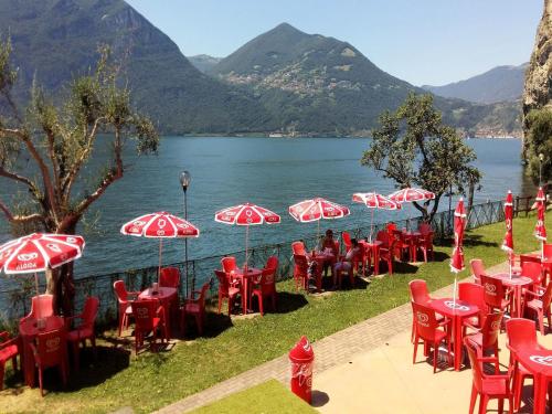 a row of red chairs and umbrellas next to a lake at Apartment in Vello by Lake Iseo Beach in Marone