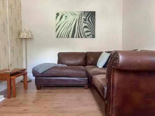 ein Wohnzimmer mit einem Ledersofa und einem Zebra-Gemälde in der Unterkunft Gwenynen Fel Cottage in Burry Port