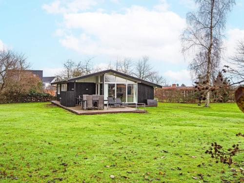 a small black house on a grassy field at 5 person holiday home in Odder-By Traum in Odder