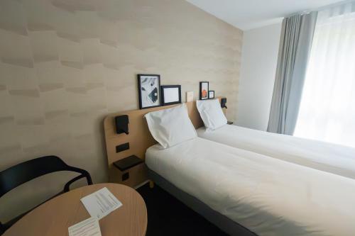 a hotel room with a large bed and a table at Nemea Appart Hotel La Boetie Bordeaux Pessac in Pessac