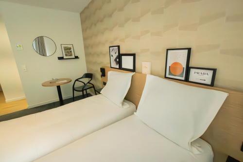 a white bed in a room with a table at Nemea Appart Hotel La Boetie Bordeaux Pessac in Pessac