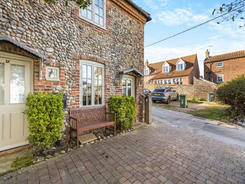 a brick house with a bench in front of it at Fishermans Cottage in Wells next the Sea