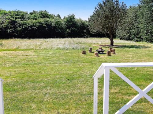 a white fence in a field with a tree at Modern Retreat at Knud Strand - By Traum Ferienwohnungen in Spottrup