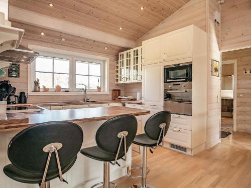 a kitchen with white cabinets and black bar stools at Modern Retreat at Knud Strand - By Traum Ferienwohnungen in Spottrup
