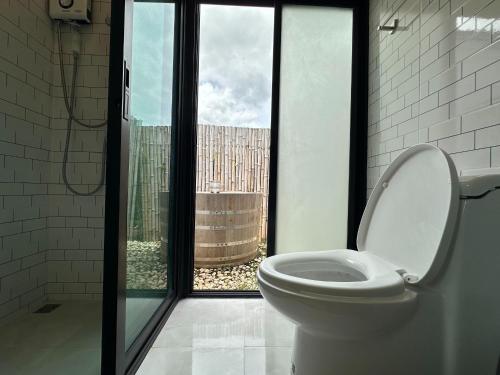 a bathroom with a toilet in front of a window at Poolla Poolla Villa Khaoyai in Pak Chong