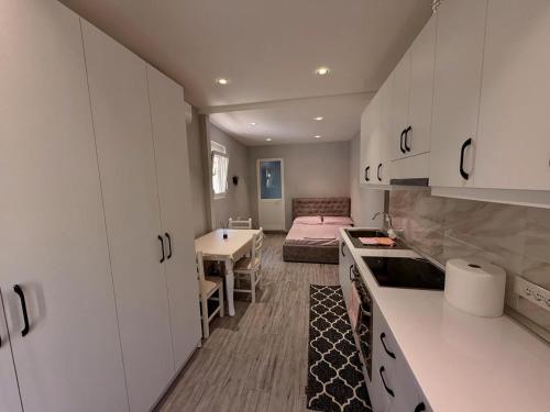 una cocina con armarios blancos y una cama en una habitación en Urban Hideaway, en Tirana
