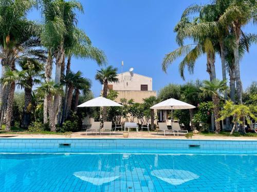 a swimming pool with chairs and umbrellas and palm trees at Villa VerdeMare Pool-Sea 300m-Nature Reserve in Plaia Grande