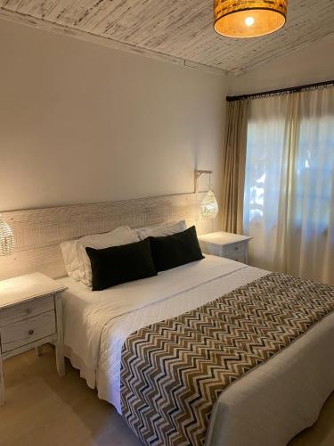 Un dormitorio con una gran cama blanca y una mesa. en Girassóis Suítes, en Pipa