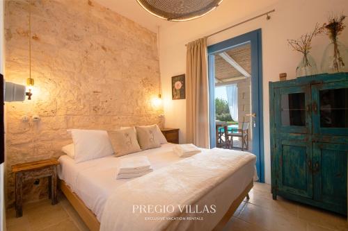 a bedroom with a large white bed with a blue door at I Trulli del Tarassaco with private pool by Pregio Villas in Martina Franca