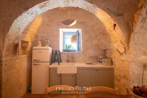 a kitchen with a white refrigerator and a window at I Trulli del Tarassaco with private pool by Pregio Villas in Martina Franca