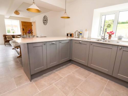 cocina con armarios grises y suelo de baldosa en Isfryn, en Mold