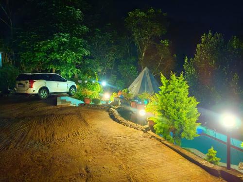 a white car parked on a dirt road at night at Misty valley Private Pool Villa Munnar in Anachal