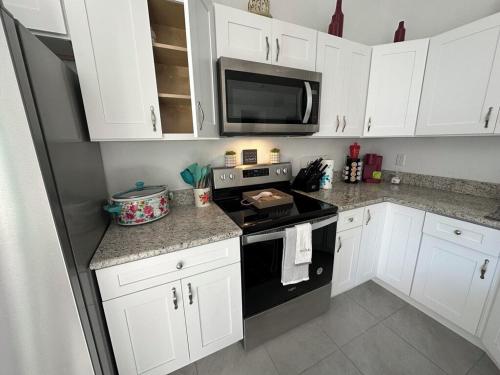 a kitchen with white cabinets and a black stove top oven at 3 Bed 2 Bath Sleeps 6 Pool Retreat in Eustis, FL!!! in Eustis