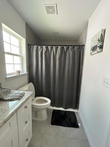 a bathroom with a toilet and a shower curtain at 3 Bed 2 Bath Sleeps 6 Pool Retreat in Eustis, FL!!! in Eustis