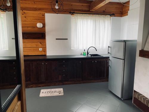 a kitchen with wooden cabinets and a refrigerator at Domek wolnostojący na terenie Hotelu Trzy Podkowy in Biskupiec