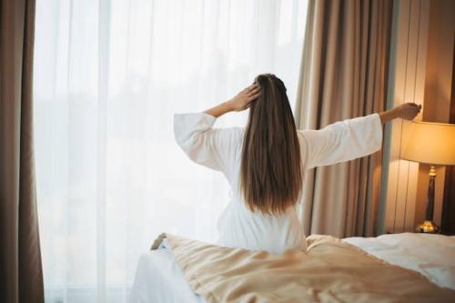 a woman is standing on a bed looking out the window at Ineza Hotel Musanze - Snow Hotel in Ruhengeri