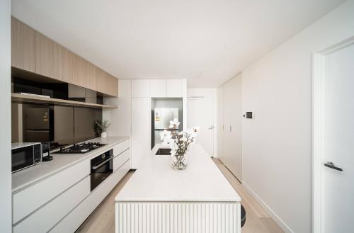 a white kitchen with a vase of flowers on a counter at Skyscraper Cinema - Dream a thousand city lights in Brisbane