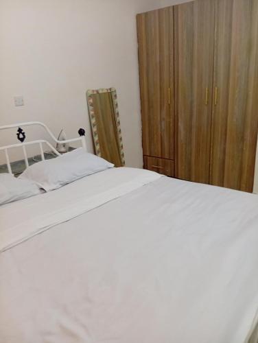 a bedroom with a white bed and a wooden cabinet at Humility - Olive in Naro Moru