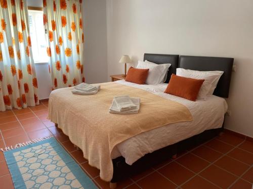 a bedroom with a large bed with orange and white pillows at 19 Aldeia Viriato in Casal da Lagoa Seca