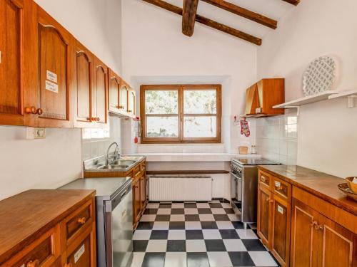 a kitchen with wooden cabinets and a checkered floor at Tuscany Villa with Terrace in Ansedónia