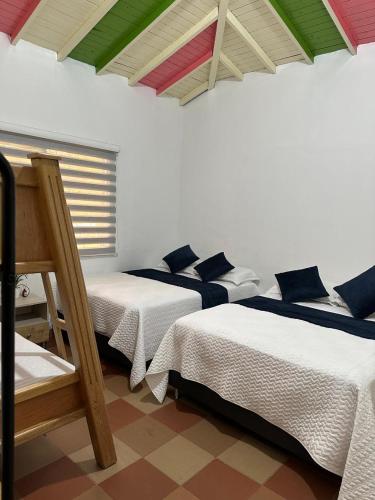 deux lits dans une chambre aux plafonds colorés dans l'établissement Refugio del Atardecer, à Guatapé