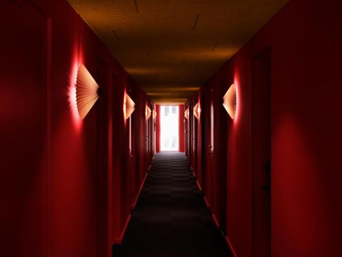 a hallway with red walls and a long corridor with a window at Dahei Apartment Hotel in Copenhagen