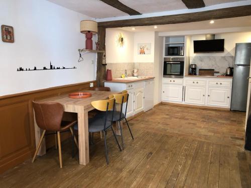 a kitchen with a wooden table and chairs and a refrigerator at Gite le 1788 in Scherwiller