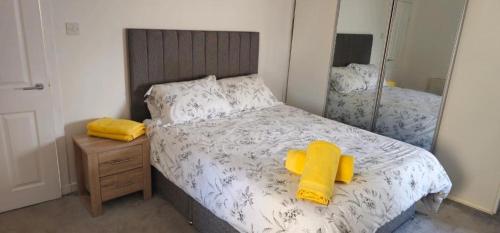 a bedroom with a bed with yellow pillows and a mirror at Coastal Bliss, Rosehearty, Fraserburgh in Rosehearty