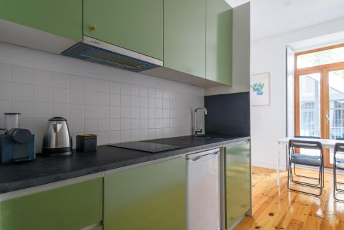 a kitchen with green cabinets and a wooden floor at Cool Alegria 1 Bed Studio Retreat in Bicas
