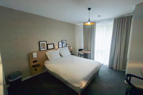 a bedroom with a white bed and a window at Nemea Appart Hotel La Boetie Bordeaux Pessac in Pessac