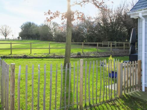 a wooden fence with a tree in a yard at Willow Cottage in Stonham Aspall