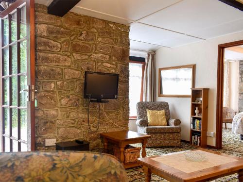 a living room with a stone wall with a tv at Lower Chinkwell-Uk12426 in Widecombe in the Moor