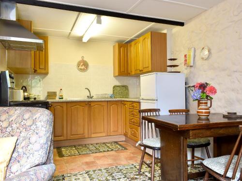 a kitchen with wooden cabinets and a table and a refrigerator at Lower Chinkwell-Uk12426 in Widecombe in the Moor