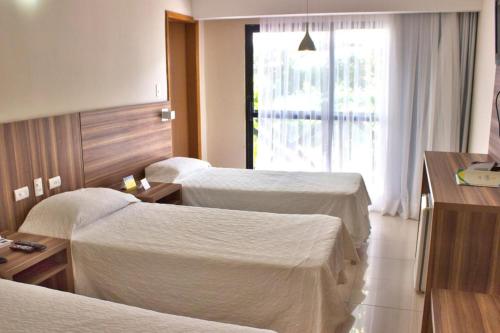 a hotel room with three beds and a window at El Aram Imirá Beach Resort in Natal