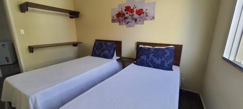 two beds with blue pillows in a room at Hotel Casa Enseada Guarujá in Guarujá