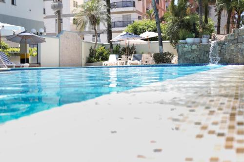 a swimming pool with chairs and umbrellas at Hotel Casa Enseada Guarujá in Guarujá