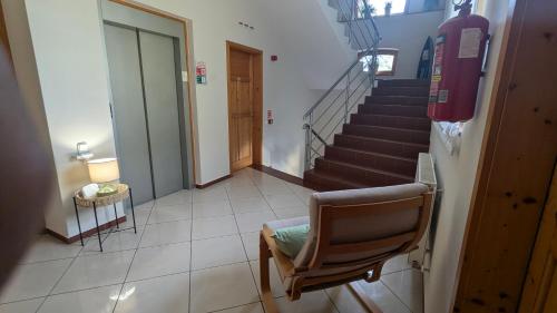 a hallway with a chair and stairs in a building at Mooi Panzió in Nagyatád