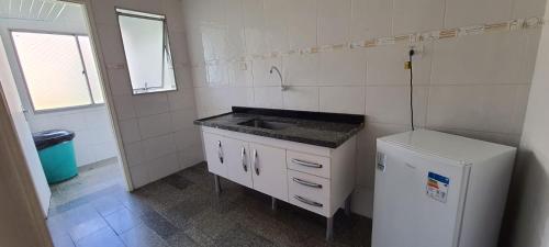 a small kitchen with a sink and a refrigerator at Hotel Casa Enseada Guarujá in Guarujá