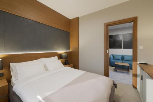 a bedroom with a large white bed and a blue couch at Hotel Orasac Garni in Belgrade