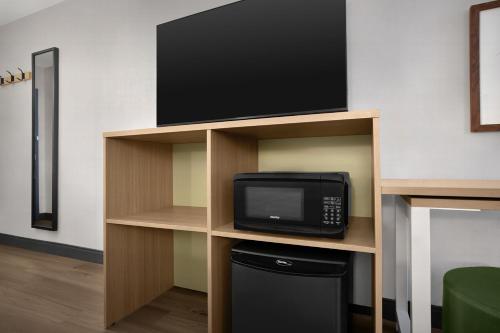 a tv on a shelf with a microwave and a television at Spark by Hilton Denver East I 70 in Denver