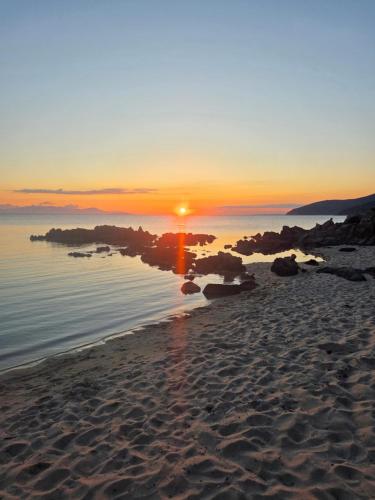 a sunset on a beach with the sun setting at Villa Di Fiore - private villa up to 10 guests with pool sauna and gym in Geremeas